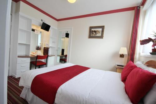 a bedroom with a red and white bed and a desk at Brig Inn in Aberdeen