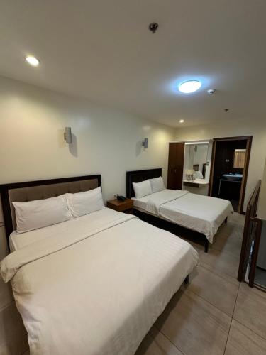 two beds in a hotel room with white sheets at Uptown Condotel in Bulwa