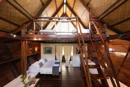 a loft bed in a room with a bed and a ladder at Harana Surf Resort in General Luna