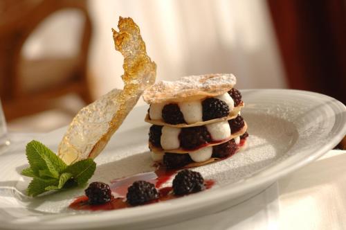 a stack of pancakes with blackberries on a plate at Hunguest Hotel Pelion in Tapolca