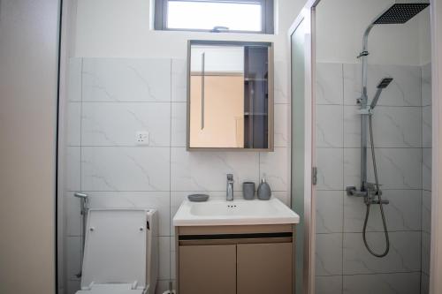 a white bathroom with a sink and a shower at Tropical Escape Flic en Flac in Flic-en-Flac