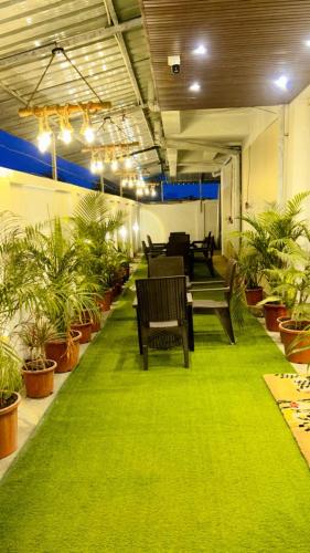 a room with a green carpet and benches and plants at Dia Inn in Bori