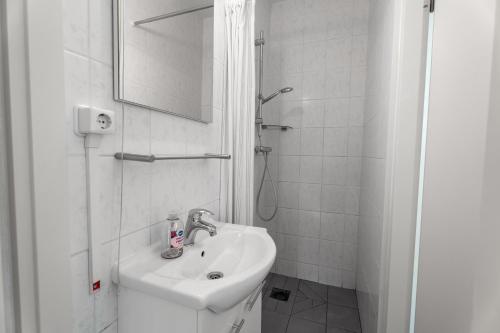 a white bathroom with a sink and a shower at Erdgeschoss-Wohnung nahe am Meer in Cadzand