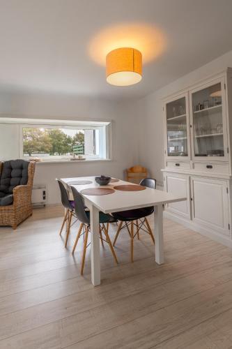 a dining room with a white table and chairs at Erdgeschoss-Wohnung nahe am Meer in Cadzand