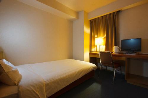 a hotel room with a bed and a desk with a computer at Sankei City Hotel Hachioji in Hachioji