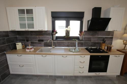 a kitchen with white cabinets and a sink and a window at Elegant Villa Punta Sol with hot tube, walk to sea and center in Jezera