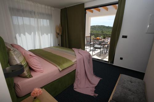 a bedroom with a bed with pink sheets and a balcony at Elegant Villa Punta Sol with hot tube, walk to sea and center in Jezera