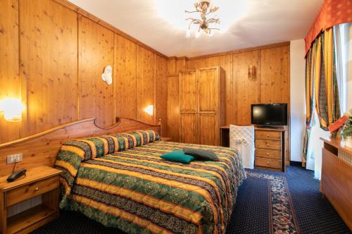 a hotel room with a bed and a television at G. Hotel Des Alpes (Classic since 1912) in San Martino di Castrozza