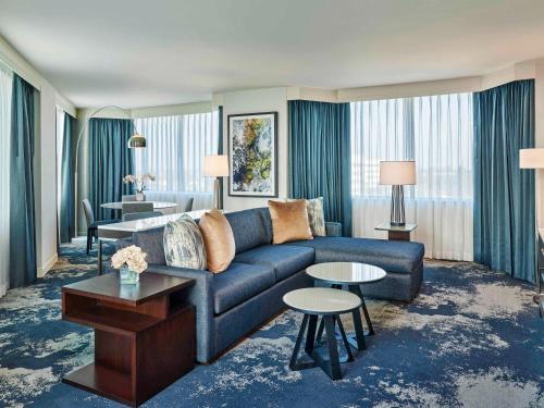 a living room with a blue couch and tables at Grand Bay Hotel San Francisco in Redwood City