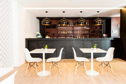 a restaurant with white tables and white chairs at Sport Hotel A Seleção in Setúbal
