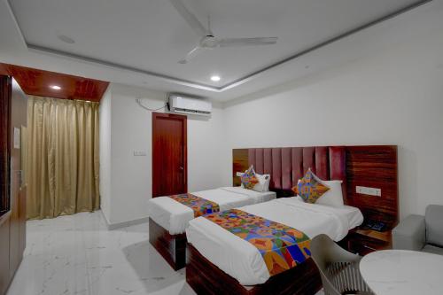 a hotel room with two beds and a table at FabHotel Palm Tree in Hyderabad