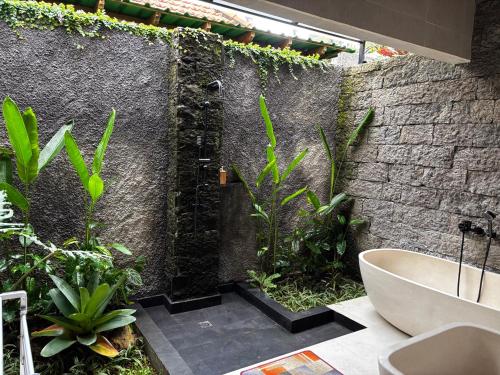 a bathroom with a bath tub and some plants at Molog private villa in Ubud