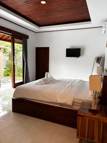 a bedroom with a large bed and a television at Molog private villa in Ubud