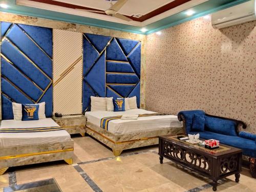 a room with two beds and a couch and a table at Moon Palace Hotel Lahore in Lahore