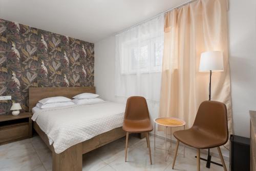 a bedroom with a bed and two chairs at Apartmany u Polanských Lednice in Lednice