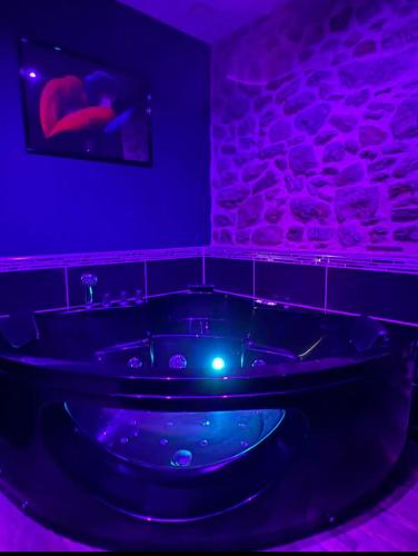 a bath tub in a room with purple lights at Spa love room in Donges