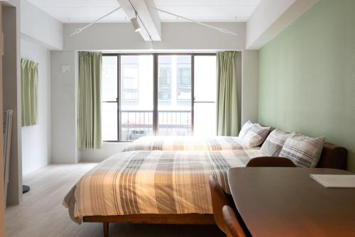 a bedroom with a bed with a table and a window at Evergreen hotel yotsuya in Tokyo