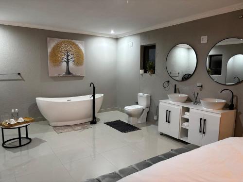 a bathroom with a tub and a toilet and two mirrors at Amahle Guesthouse Bush in Dwarsloop