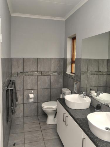 a bathroom with two sinks and a toilet and a mirror at River Bend Farm in Lidgetton