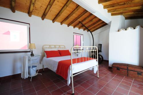 een slaapkamer met een bed met rode kussens bij Hortas de Baixo, Luz de Tavira in Tavira