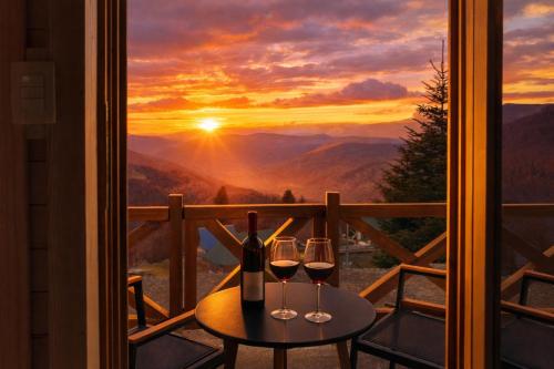 a table with two glasses of wine on a balcony at Komovi Luxury Sunset in Andrijevica