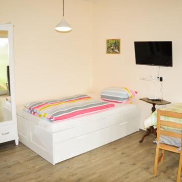 a white room with a bed and a television at Kleine Bella in Ilmmünster