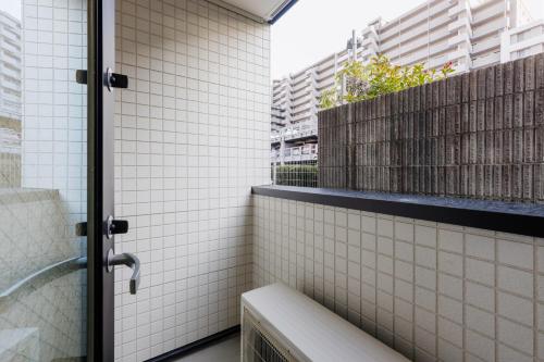 a bathroom with a shower with white tiled walls at Anecis笠取町1 in Nagoya
