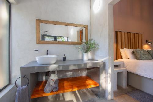 a bathroom with a sink and a mirror and a bed at Spoorzicht in Marloth Park