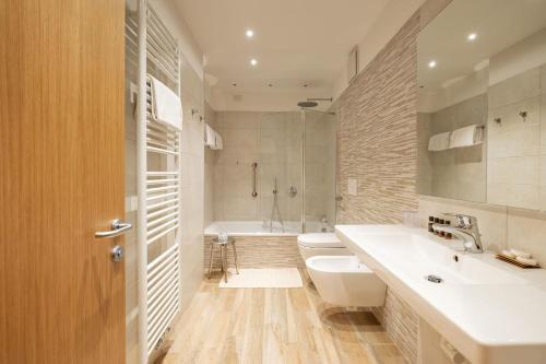a bathroom with a sink and a toilet and a tub at Hotel Pontechiesa in Cortina dʼAmpezzo