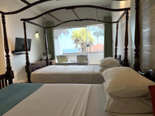 a person sitting on a bed in a bedroom at Sri Gemunu Beach Resort in Unawatuna