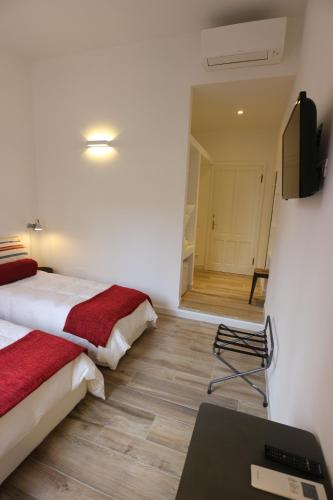 a room with two beds and a desk and a television at AL 32 B&B in Massa Marittima