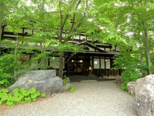 a building with trees and rocks in front of it at Bunanoyado Koase in Aga