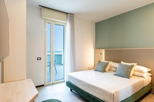 a bedroom with a large bed and a balcony at Hotel Acquamarina Viserba in Rimini
