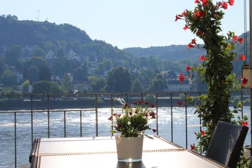 a table with flowers on a balcony overlooking the water at RheinHotel ARTE in Remagen
