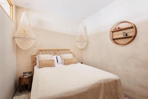 a bedroom with a bed with white sheets and chandeliers at I Boho Sun Oceanfront Apartment in Icod de los Vinos