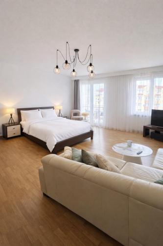 a white bedroom with a bed and a couch at Plac 14- Apartamenty i pokoje w centrum in Świnoujście