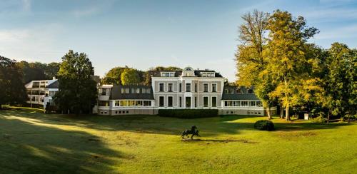 a man riding a horse in front of a large house at Landgoed Lauswolt in Beetsterzwaag