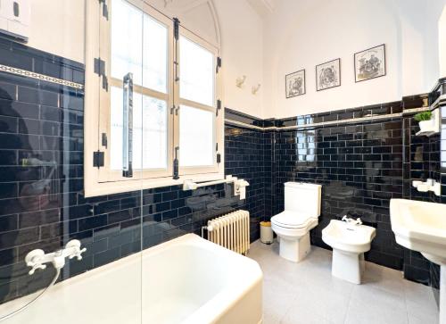 a bathroom with a toilet and a tub and a sink at Almaterra Apartamentos Turísticos in Huéscar