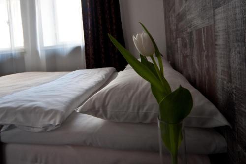 a vase with a flower in it next to a bed at Merchants House Hotel in Tallinn