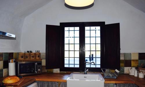 a kitchen with a sink and two large windows at Cuevas Helena in Benamaurel