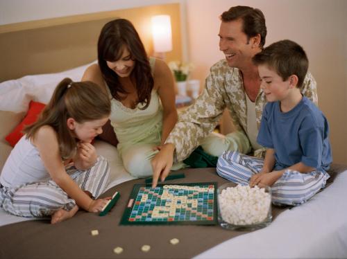 a family playing a board game on a bed at Novotel Basel City in Basel