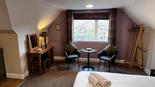 a room with a bed and two chairs and a table at Springburn Farmhouse in Spean Bridge