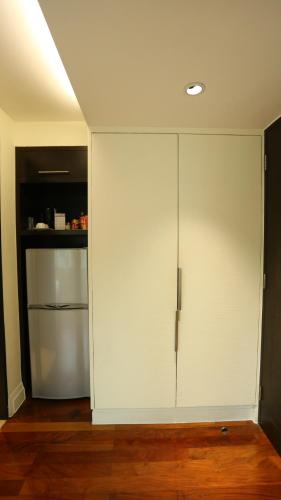 a white cabinet in a room with a refrigerator at The Quarter Saladaeng by UHG in Bangkok