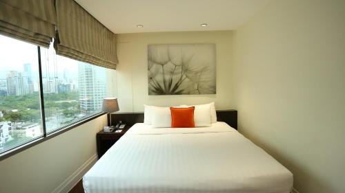 a bedroom with a white bed with an orange pillow at The Quarter Saladaeng by UHG in Bangkok