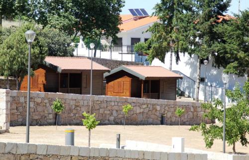 two wooden huts behind a stone wall at Douro Camping in Miranda do Douro