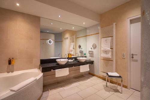 a bathroom with two sinks and a bath tub at Aqua Aurelia Suitenhotel an den Thermen in Baden-Baden