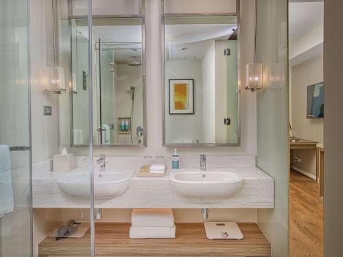 a bathroom with two sinks and a shower at Novotel Suites at Acqua in Manila