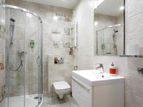 uma casa de banho com um lavatório e um chuveiro. em Manhattan Place Apartament em Varsóvia