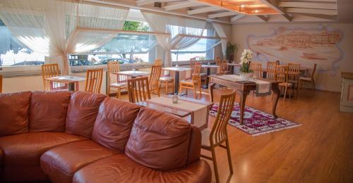 un divano in pelle in un ristorante con tavoli e sedie di Hotel Aquadolce a Verbania