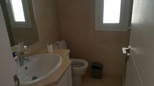 a bathroom with a sink and a toilet and two windows at Twin Lagoon Apartment at White Villas El Gouna in Hurghada